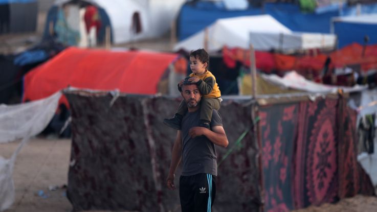 A man carrying his child on his shoulders at a camp in Gaza for displaced Palestinians.